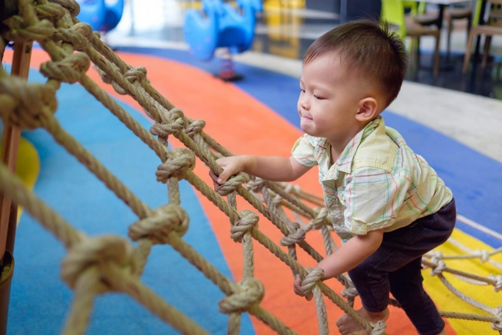 a child climbing a wooden ladder connecting to a playground