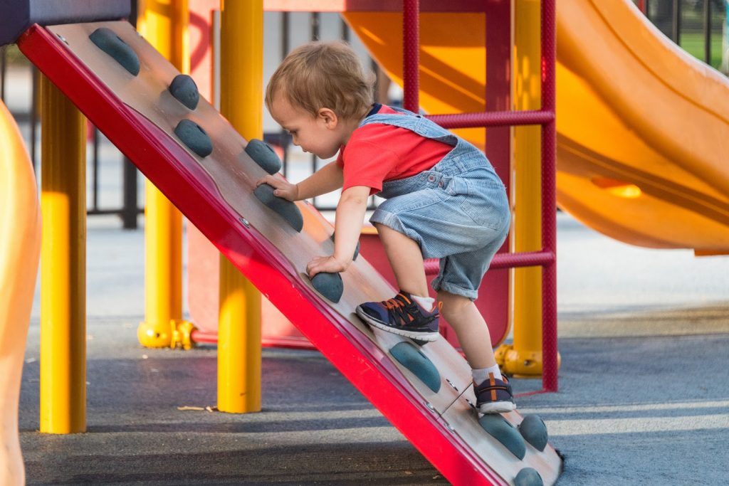 a young boy climbing up a playsystem