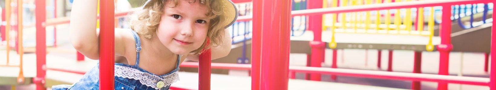 A yound child sitting on a playground.