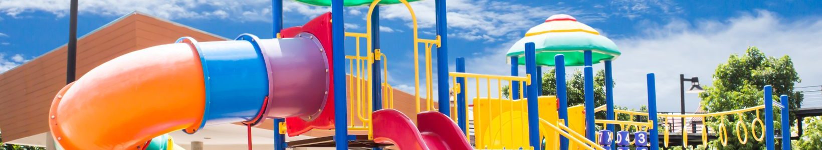 An outdoor playground with multiple slides, monkey bars and an activity panel.