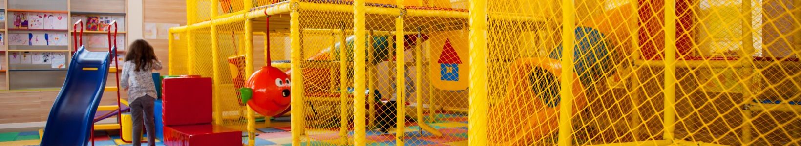 A yellow indoor playground with a small child playing.
