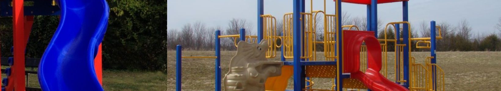 A colorful playground with a blue twisty slide on the left and a multi-level play structure featuring red roofs, blue and yellow bars, and slides on the right.